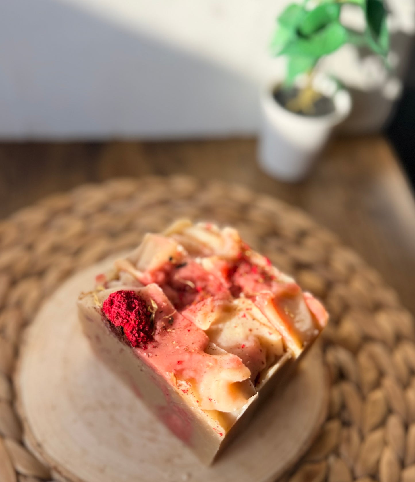 Top view of Eden Body Care Pomegranate Flowers handmade soap with pink and cream swirls, sculpted top, and dried floral accents.