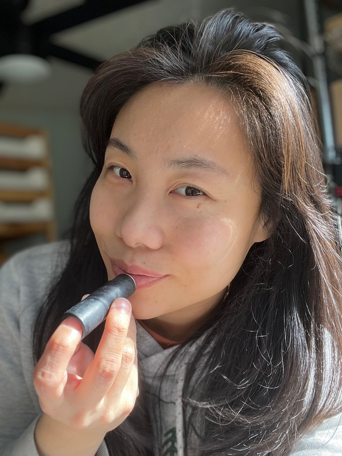 Woman applying Eden Body Care lip balm directly to her lips in natural light.