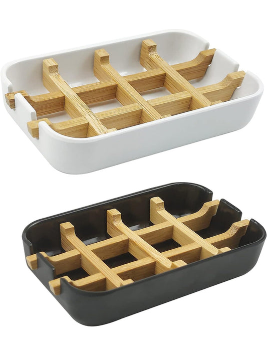 White and black draining soap dishes with raised bamboo slats designed to keep handmade soap bars elevated and dry between uses.