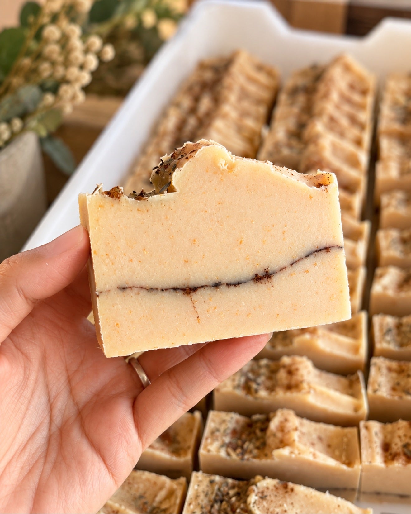Handmade Home for Fall soap bar held in hand, scented with evergreen, cinnamon, apple, and fresh linen, with a cinnamon line through the center.