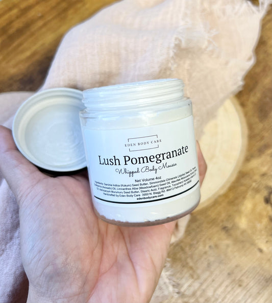 Open jar of Eden Body Care Lush Pomegranate whipped body mousse held in hand, showing the creamy whipped texture inside.