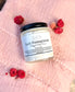 Eden Body Care Lush Pomegranate whipped body mousse jar displayed on soft pink fabric with dried red and pink flowers.