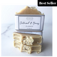 Stack of beige oatmeal and honey goat milk soap bars with oatmeal pieces on top, placed on a white surface with a paper cigar band packaging.