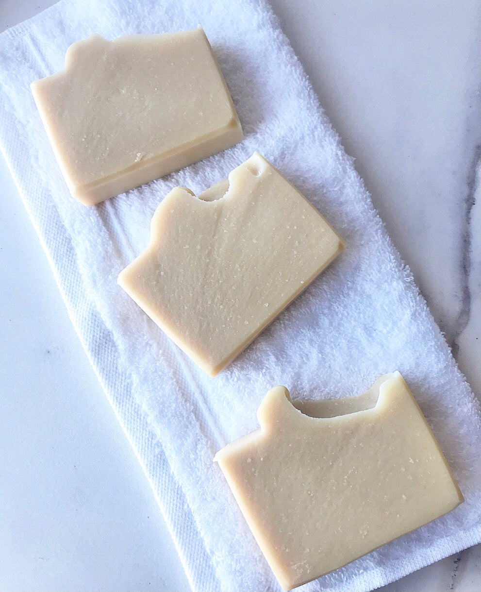 Three Eden Body Care Classic Unscented goat milk soap bars arranged on a folded white towel in a clean flat-lay display