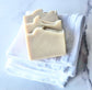 Three Eden Body Care Classic Unscented goat milk soap bars arranged on a folded white towel.