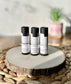 Three Eden Body Care lip balm tubes in Unscented, Vanilla Mint, and Lemon Lavender displayed together on a natural wood slice.