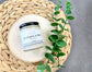 Eden Body Care Eucalyptus & Mint body mousse jar displayed on a natural wood slice beside green eucalyptus-style leaves