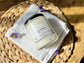 Eden Body Care Lavender whipped body mousse jar displayed on a white towel with dried purple flowers in warm natural light.
