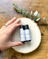 Two Eden Body Care lip balm tubes, Lemon Lavender and Lavender, displayed on a natural wood slice and held by hand.