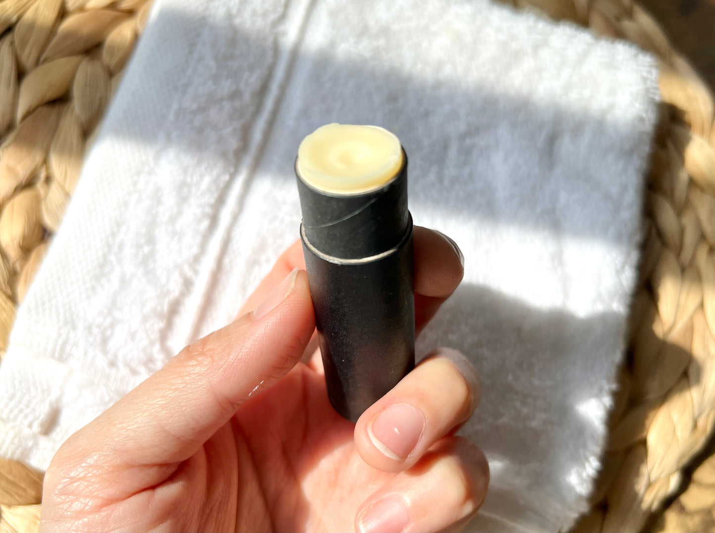 Close-up of an open Eden Body Care lip balm tube held in hand, showing the pale natural balm inside.
