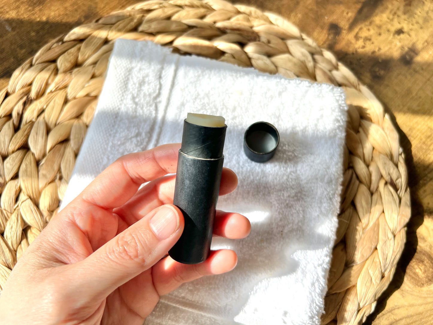 Close-up of an open Eden Body Care lip balm tube held in hand, showing the pale natural balm inside cap off