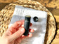 Close-up of an open Eden Body Care lip balm tube held in hand, showing the pale natural balm inside cap off