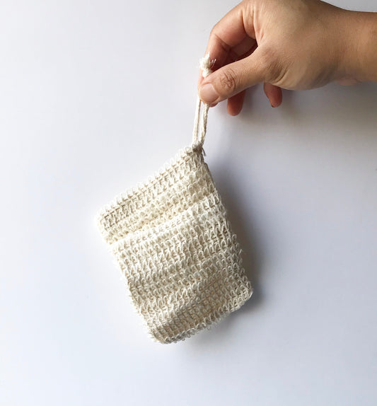 A hand holding a beige ramie soap jacket against a white background